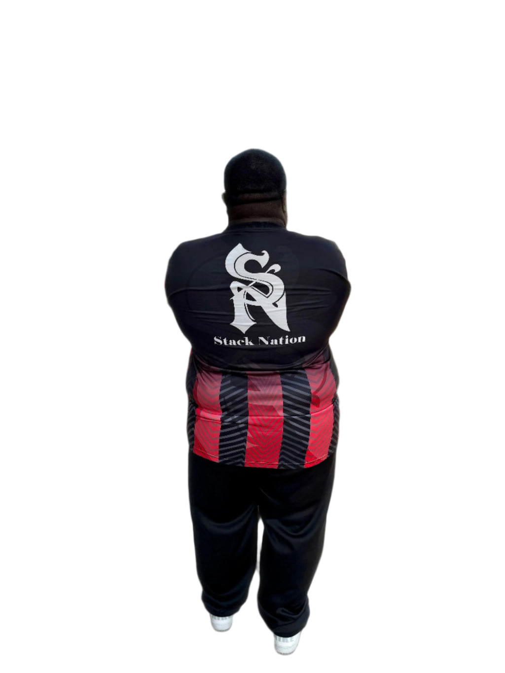 Person wearing a black tracksuit with 'Stack Nation' branding, walking on a street.